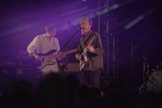 Jack Tatum singing and playing guitar beside a bassist under purple stage lights at Field Day in London